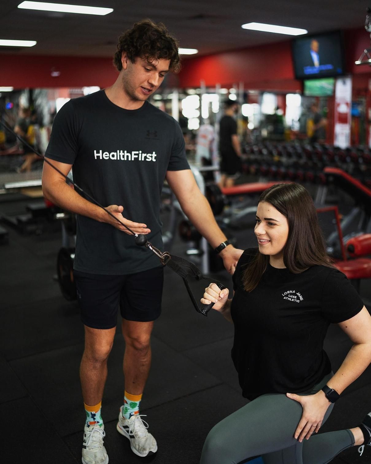 A Man is Helping a Woman Do Exercises in a Gym β Health First Townsville In Townsville, QLD