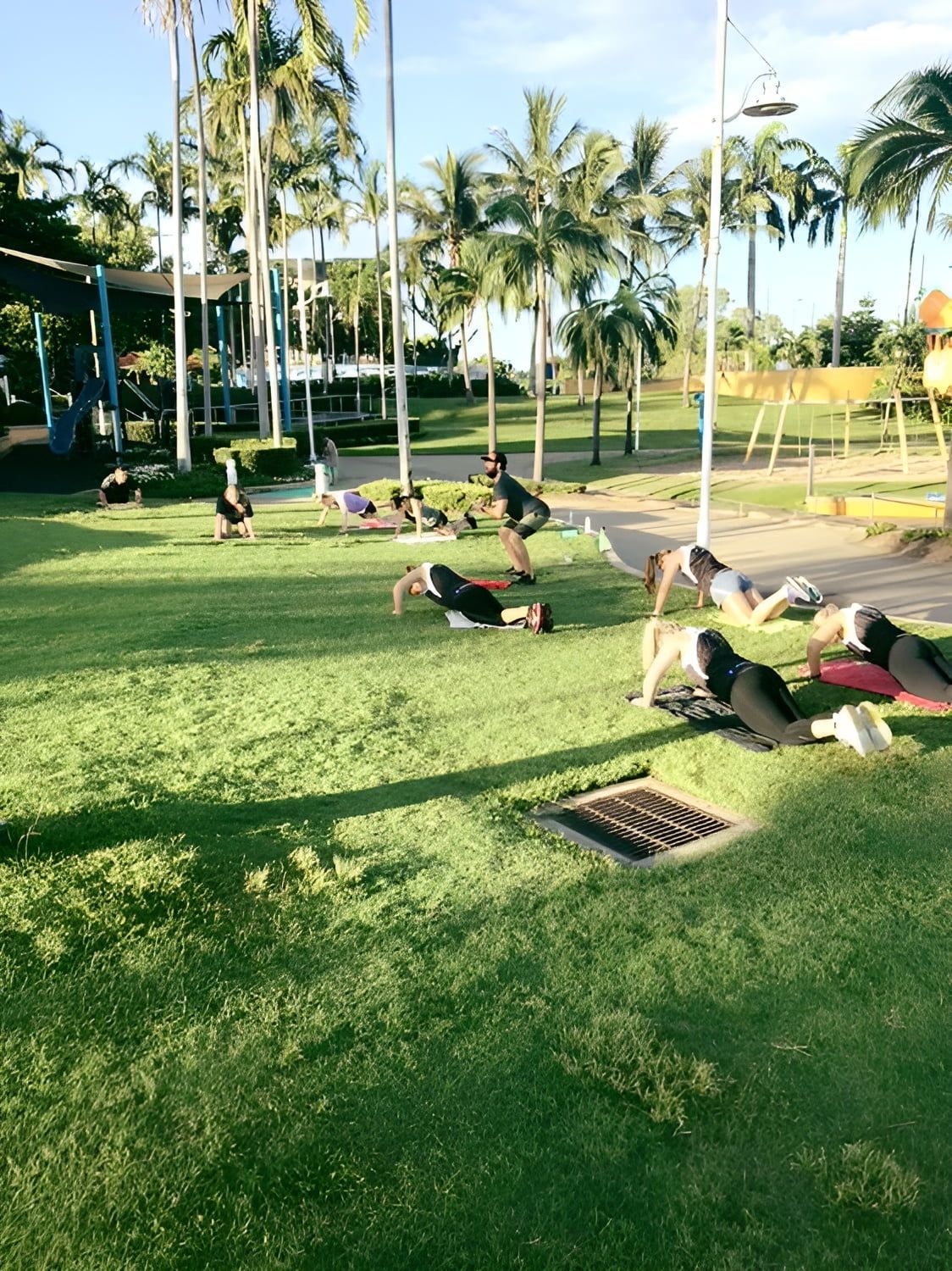 A Group of People Are Doing Push Ups on the Grass in a Park — Health First Townsville In Townsville, QLD