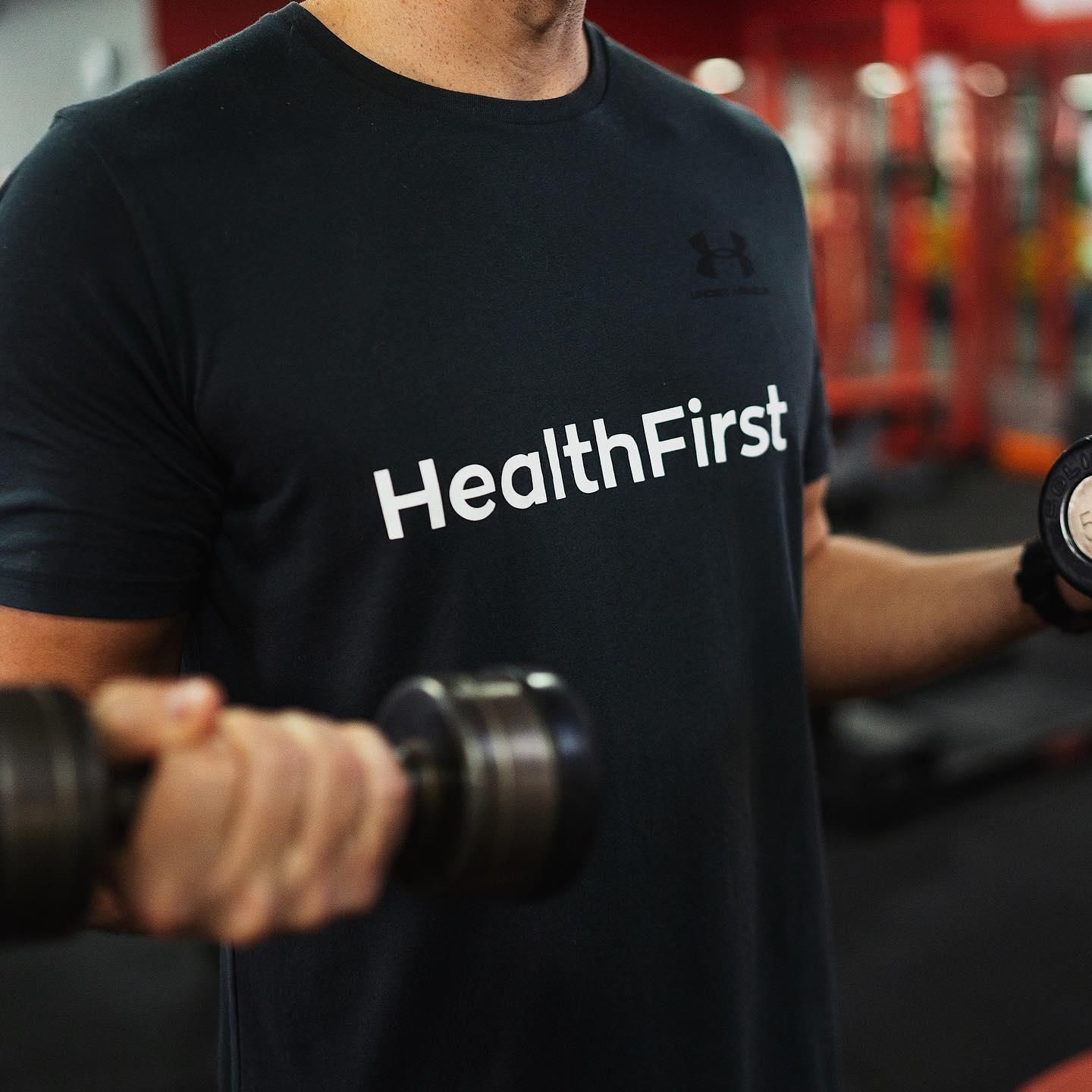 A Man is Squatting With a Barbell in a Gym β Health First Townsville In Townsville, QLD