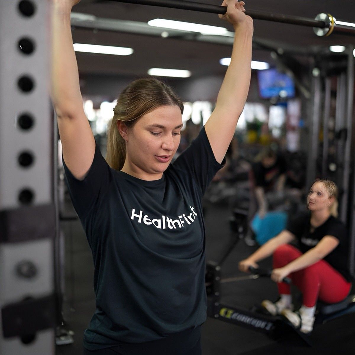 A Woman is Helping an Older Woman Do Exercises in a Gym — Health First Townsville In Townsville, QLD