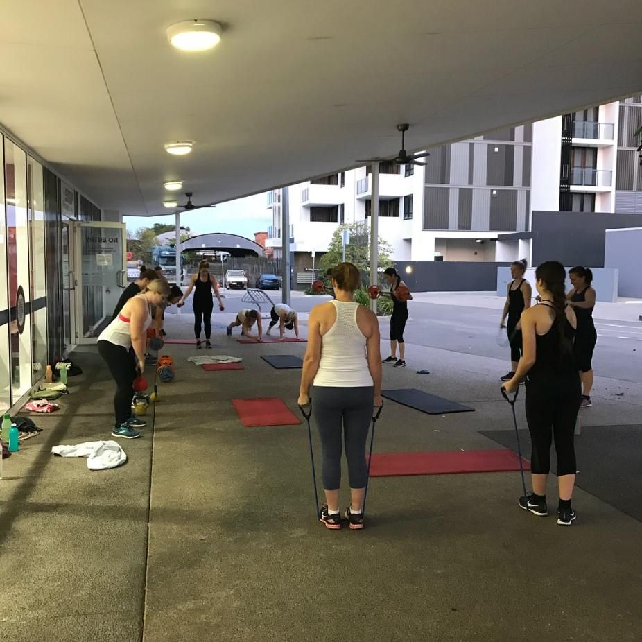 A Group of People Are Doing Exercises on a Sidewalk — Health First Townsville In Townsville, QLD