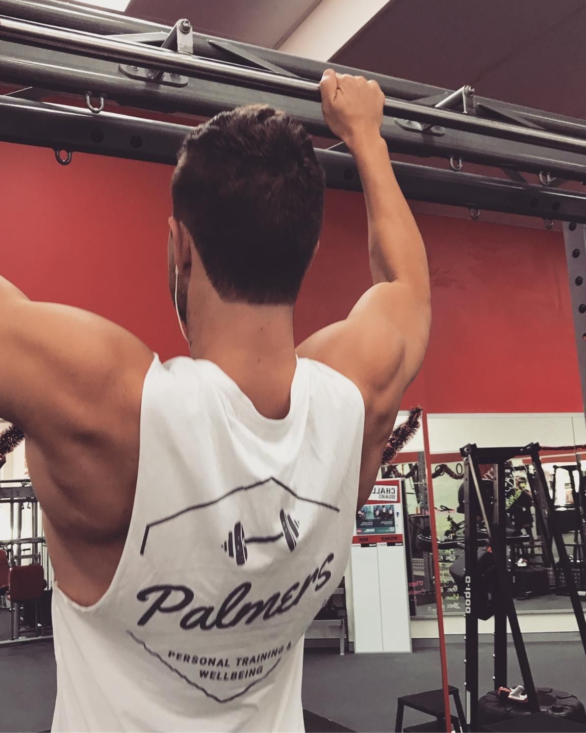 A Man Wearing a Palmer 's Tank Top is Doing Pull Ups β Health First Townsville In Townsville, QLD