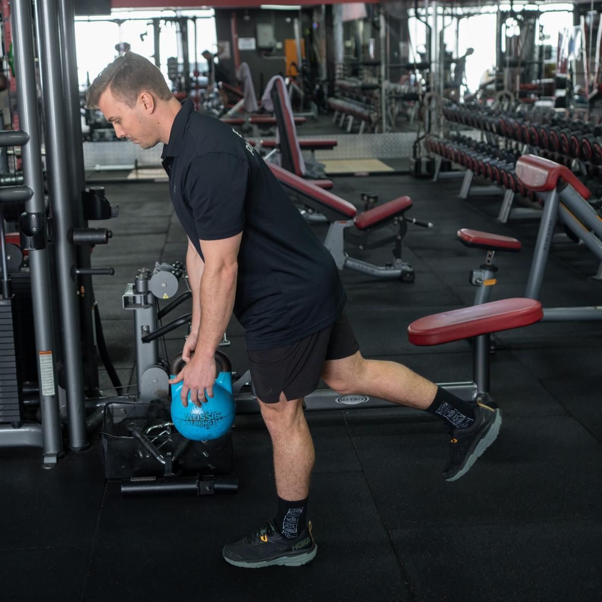 A Man is Holding a Blue Kettlebell in a Gym β Health First Townsville In Townsville, QLD