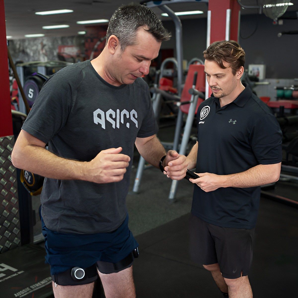 A Man Wearing an Asics Shirt Talks to Another Man in a Gym β Health First Townsville In Townsville, QLD