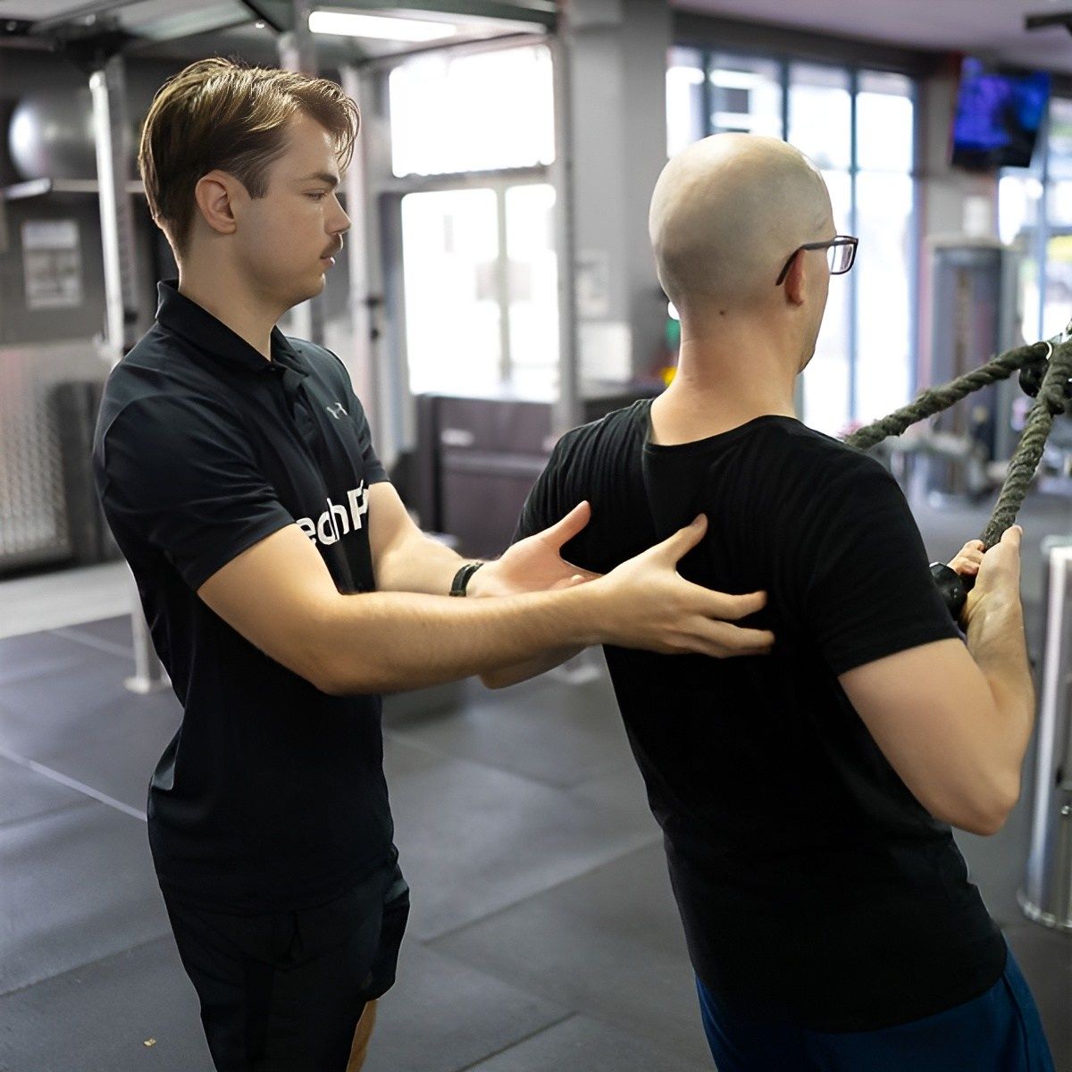 A Man is Helping Another Man Lift a Rope in a Gym β Health First Townsville In Townsville, QLD