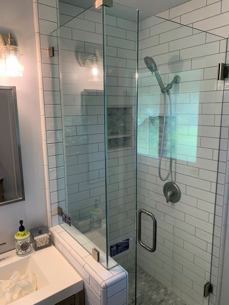 A bathroom with white tiles and a glass shower door.
