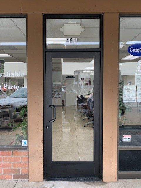 The front door of a store with a car parked in front of it.