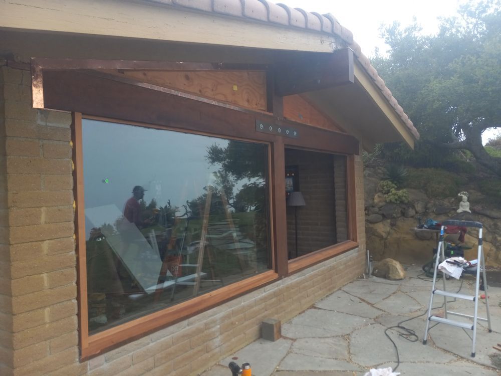 A ladder sits in front of a large window on a brick building