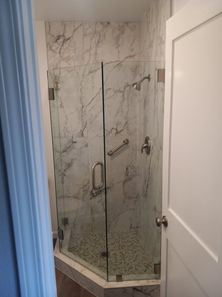A bathroom with a glass shower door and marble walls.
