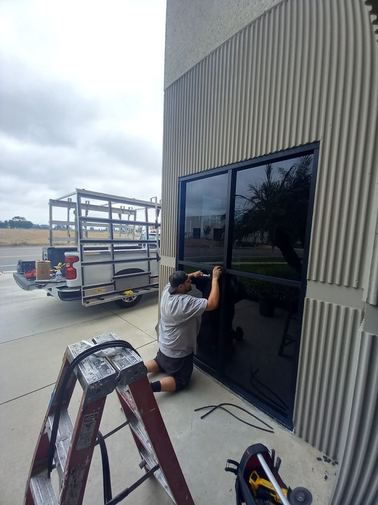 A man is installing window tinting on a building.