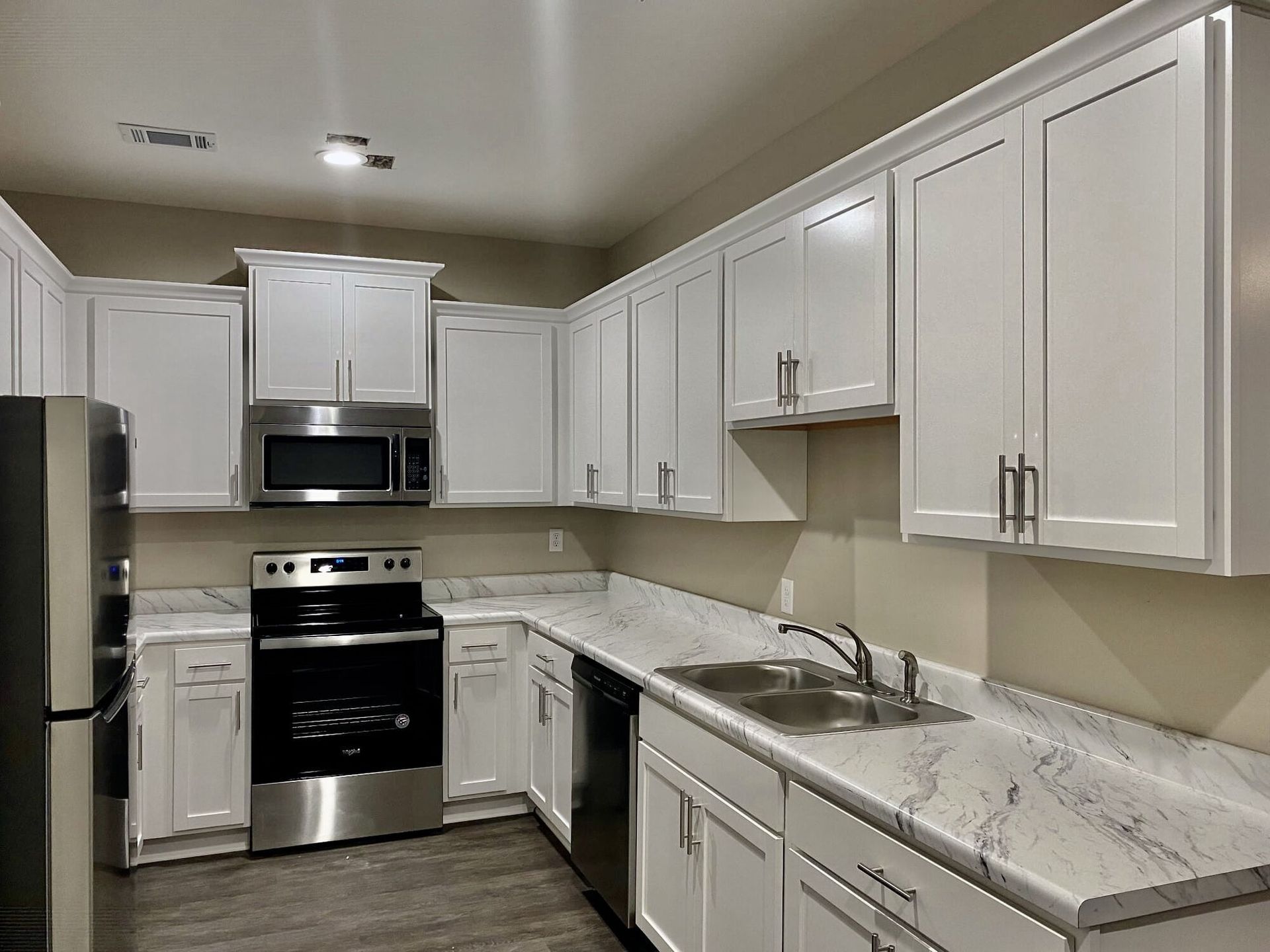 A kitchen with white cabinets and stainless steel appliancesat Patriots Place.
