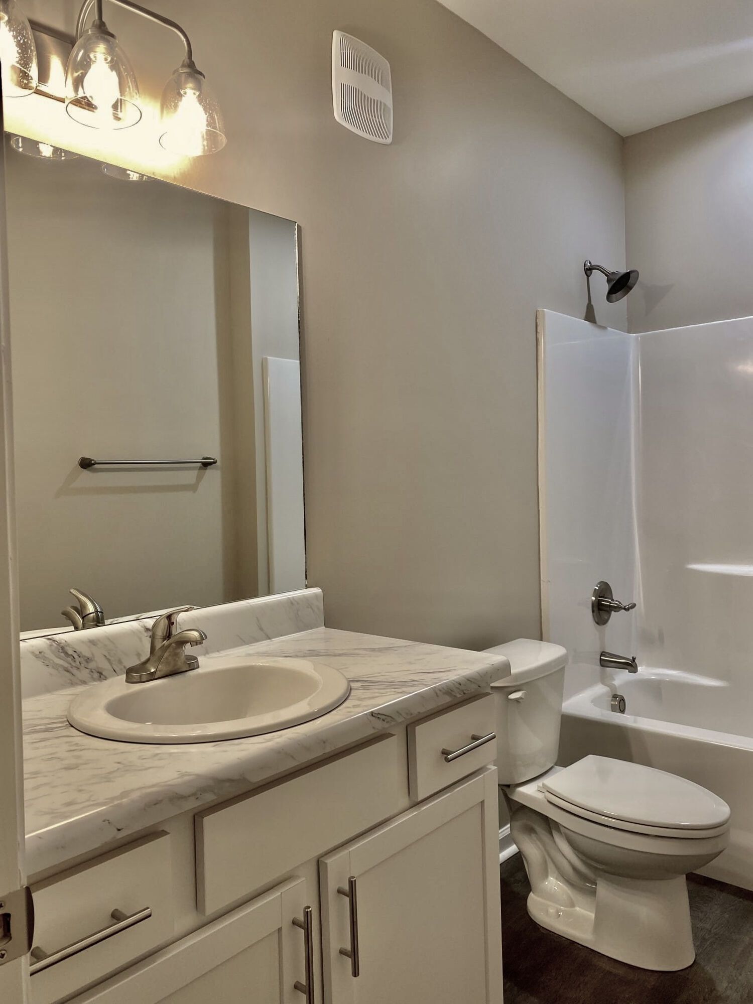A bathroom with a sink , toilet , tub and mirror at Patriots Place.