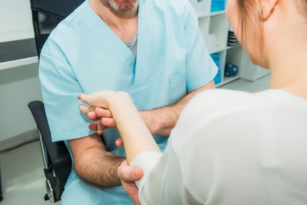 A Doctor Is Examining a Patient 's Arm in A Hospital — AMC Exercise Physiology in Maitland, NSW