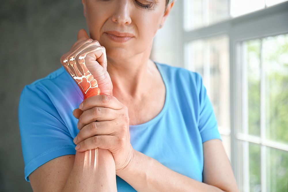 A Woman is Holding Her Wrist in Pain — AMC Exercise Physiology in Maitland, NSW