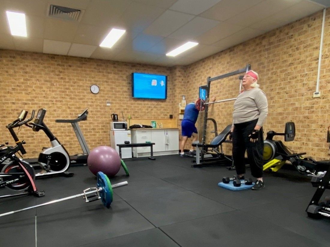 A man and a woman are standing in a gym — AMC Exercise Physiology in Maitland, NSW
