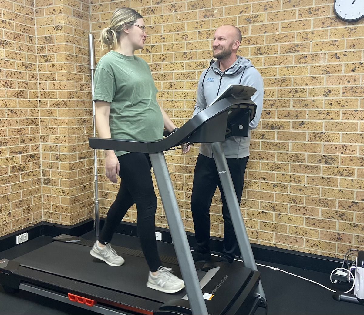 A woman is sitting on an exercise ball with a resistance band — AMC Exercise Physiology in Maitland, NSW
