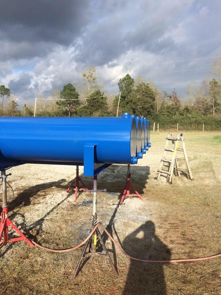 a row of blue pipes are sitting on top of each other in a field .