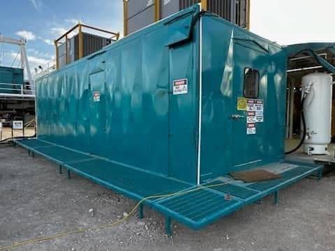 a large blue building is sitting on top of a dirt field .