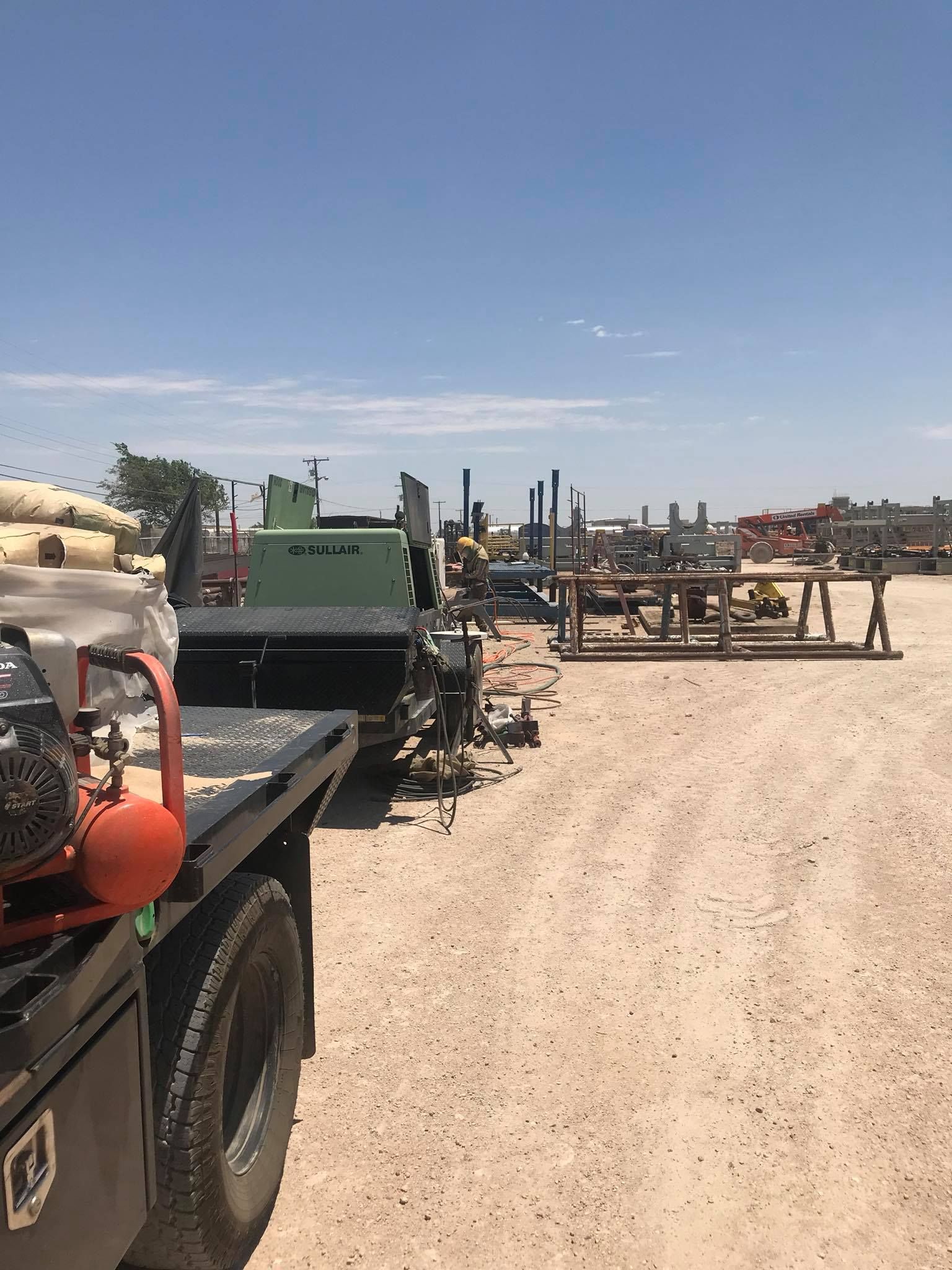 a truck with a compressor on the back of it is parked in a dirt lot .