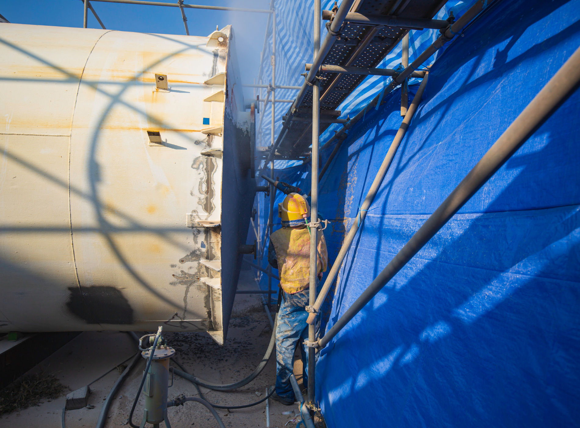 a man is standing on a scaffolding next to a large tank .