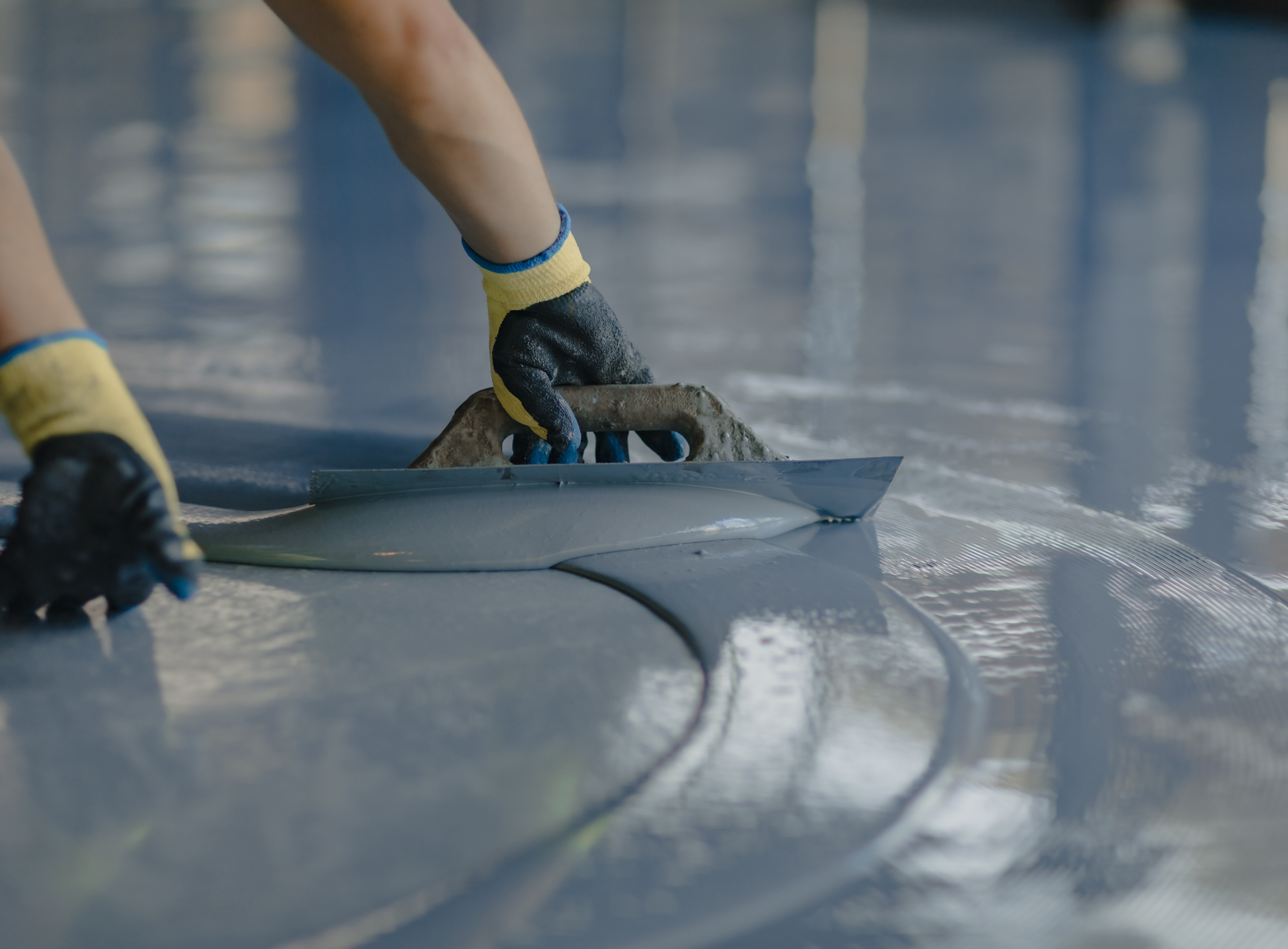 a person is using a trowel on a concrete floor .