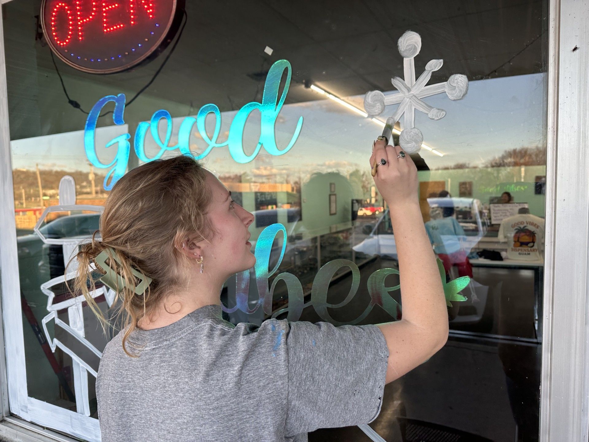 Stilwell artist Abigail Rust painting a window on a local business.