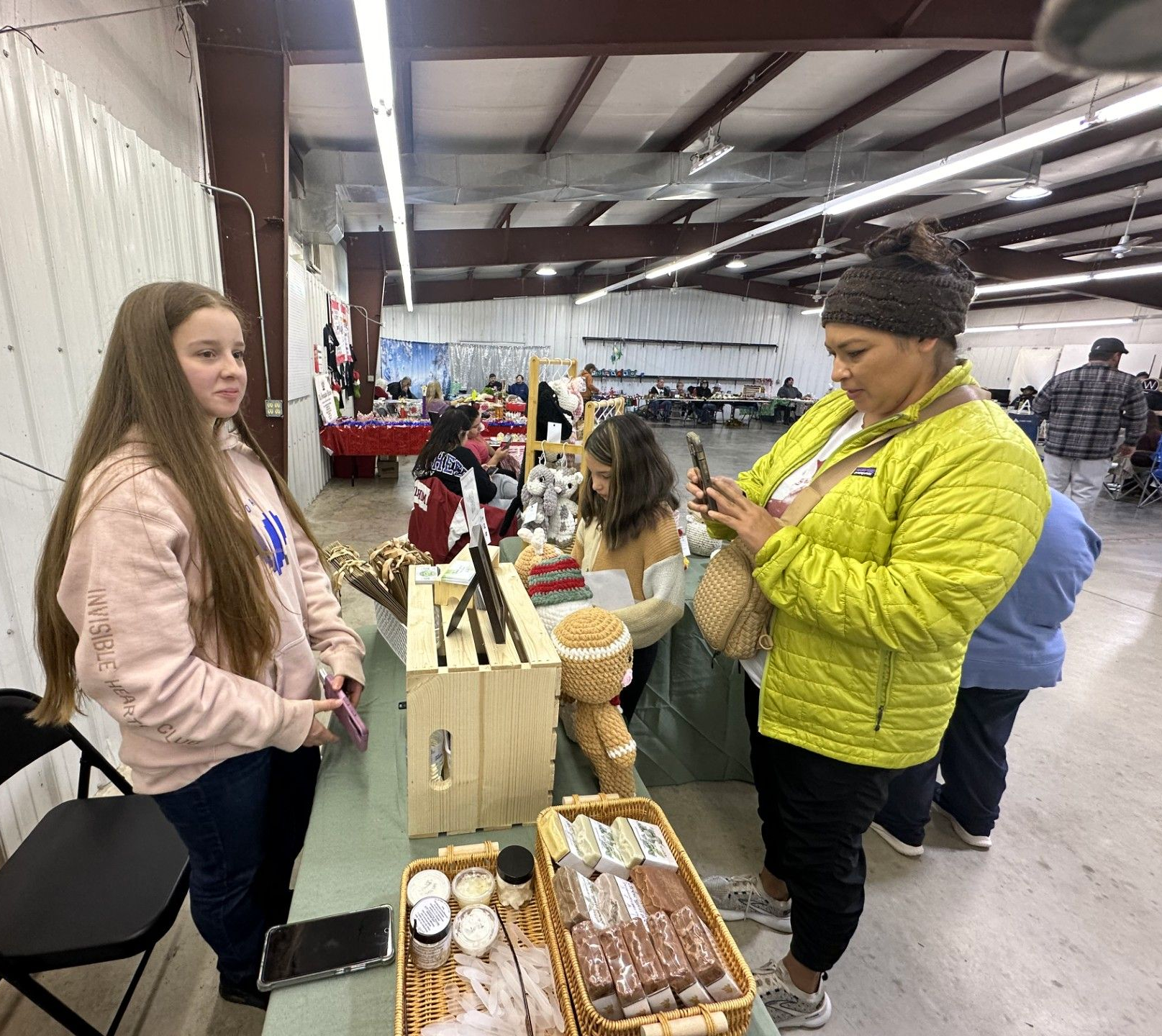 Breanna Green with Honey Hill Farmstead helps Jada Nofire with a purchase, as her daughter, Kyloa Nofire looks at stuffed animals.
