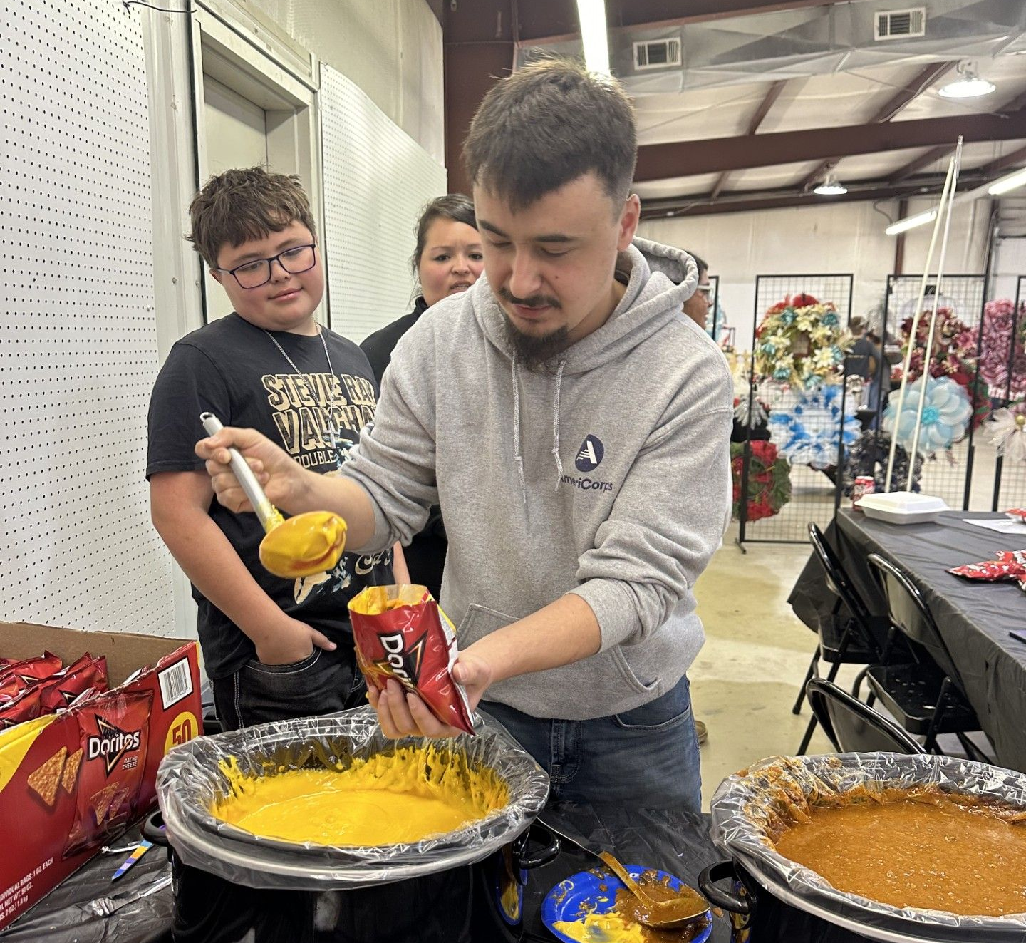 Boys and Girls Club Vista Volunteer Kyle Steward fills a Walking Taco for Kingston Boyce.