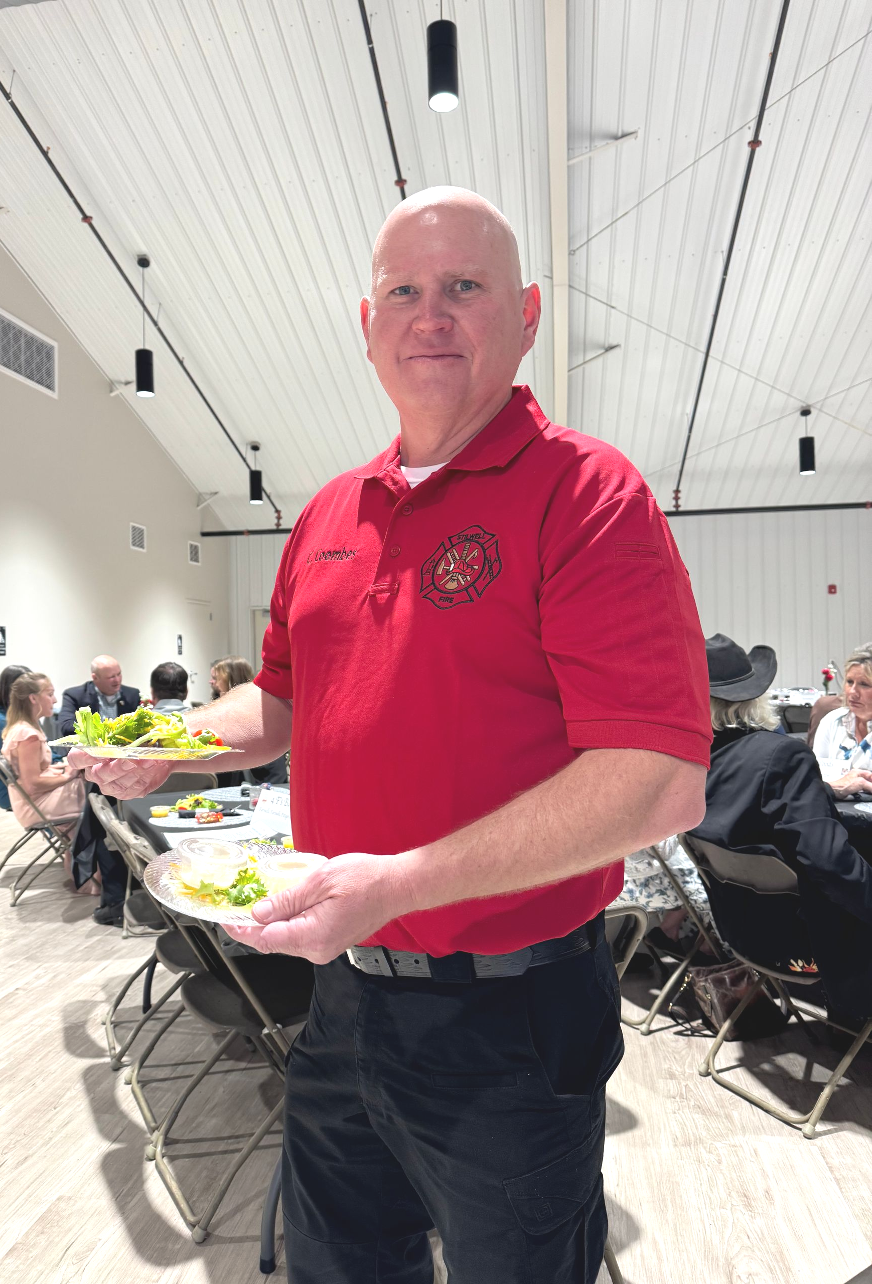 Stilwell Fire Chief Charley Coombes clears a table. Firefighter volunteers served meals and cleaned up afterward.