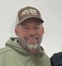 A man with a beard is wearing a hat and a green hoodie.