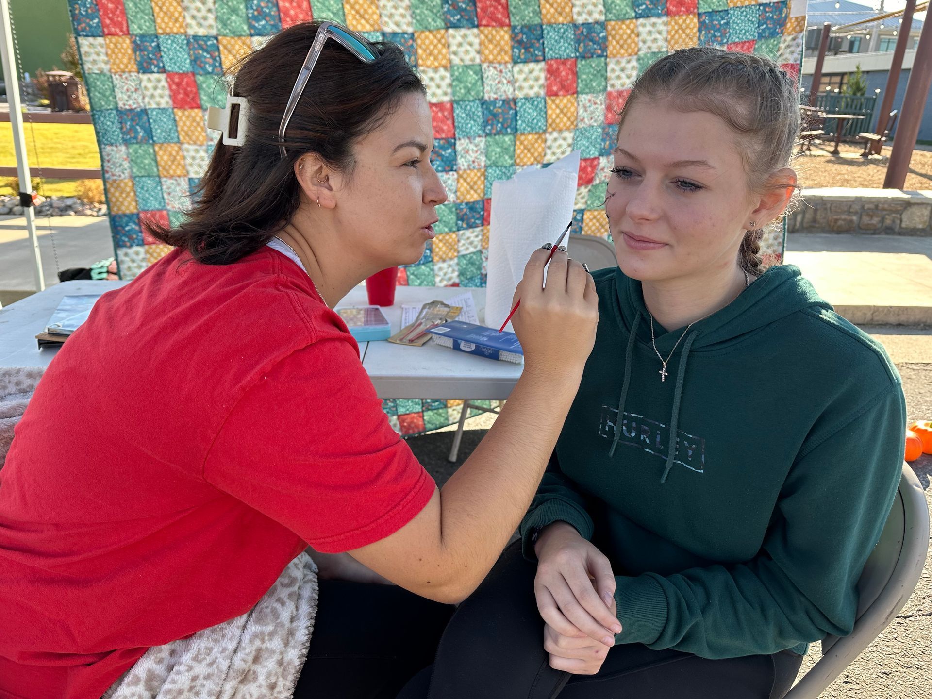 A woman is applying makeup to a young girl 's face.