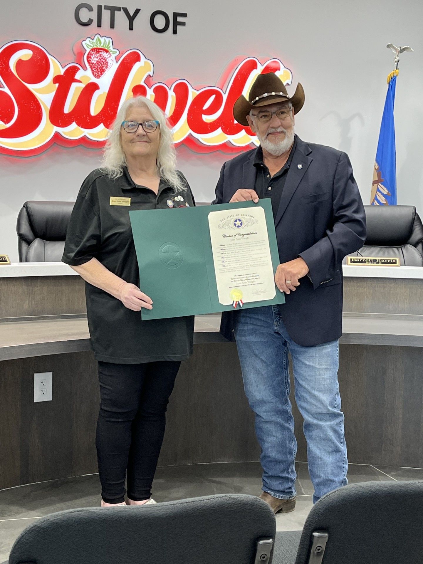 A man and a woman are standing next to each other holding a certificate.