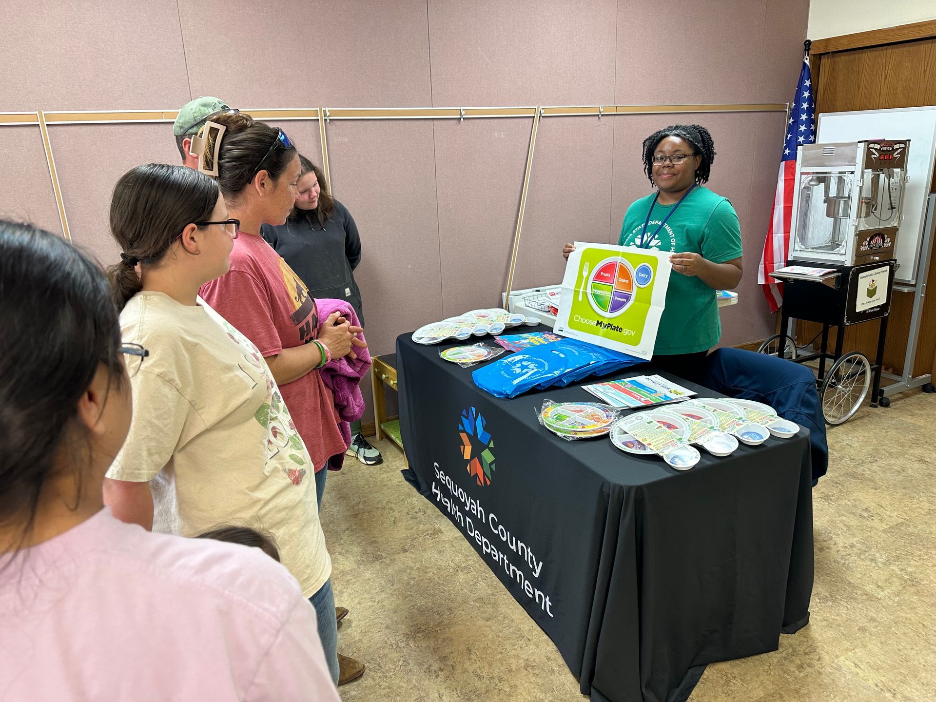A woman is standing in front of a table with a sign on it.