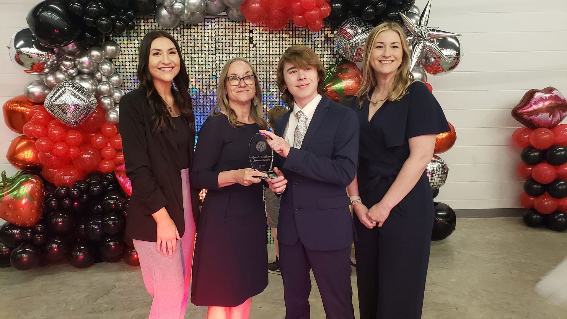 A group of people standing next to each other in front of balloons.