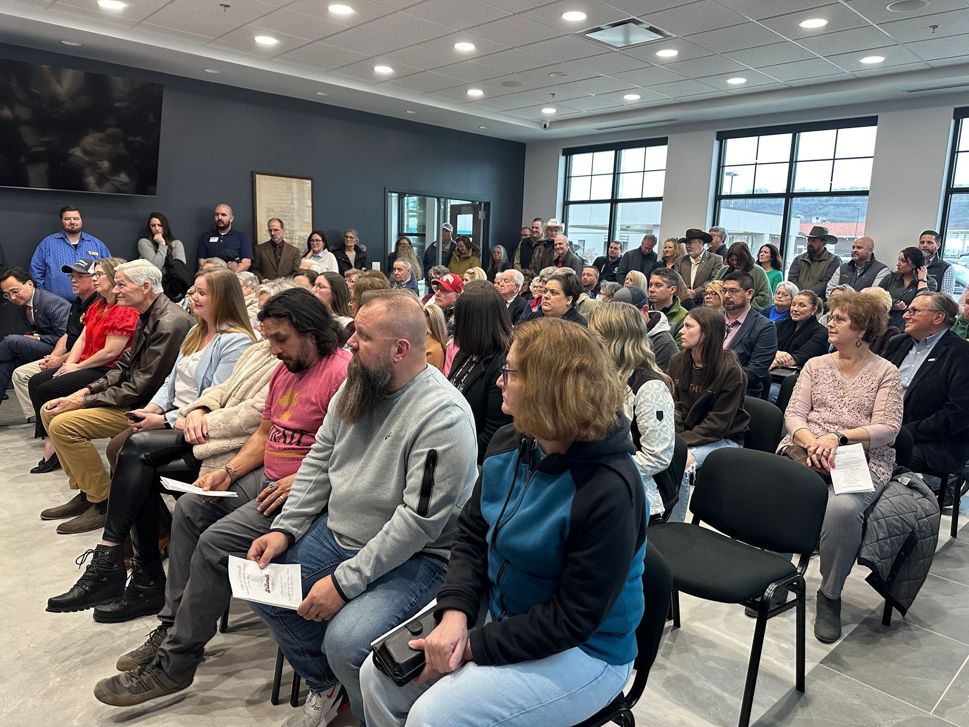 A large group of people are sitting in chairs in a room.