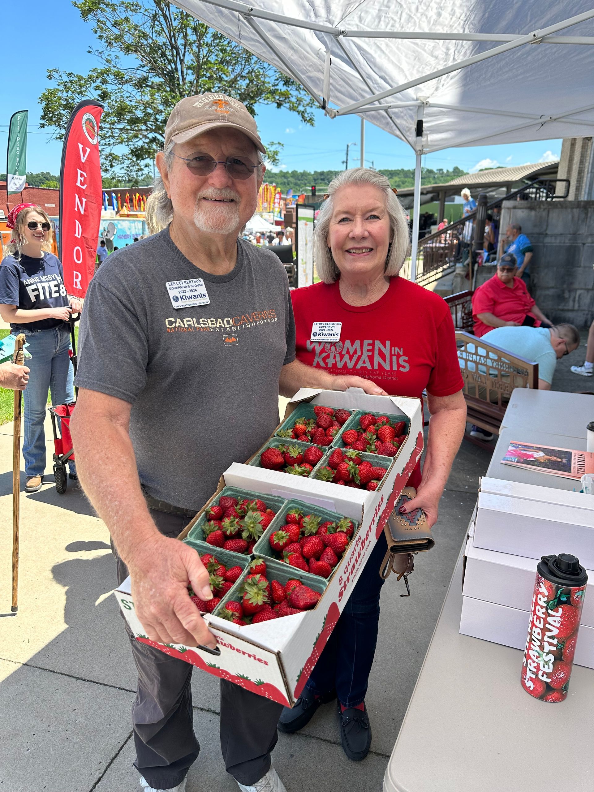 A man and a woman are holding boxes of strawberries.