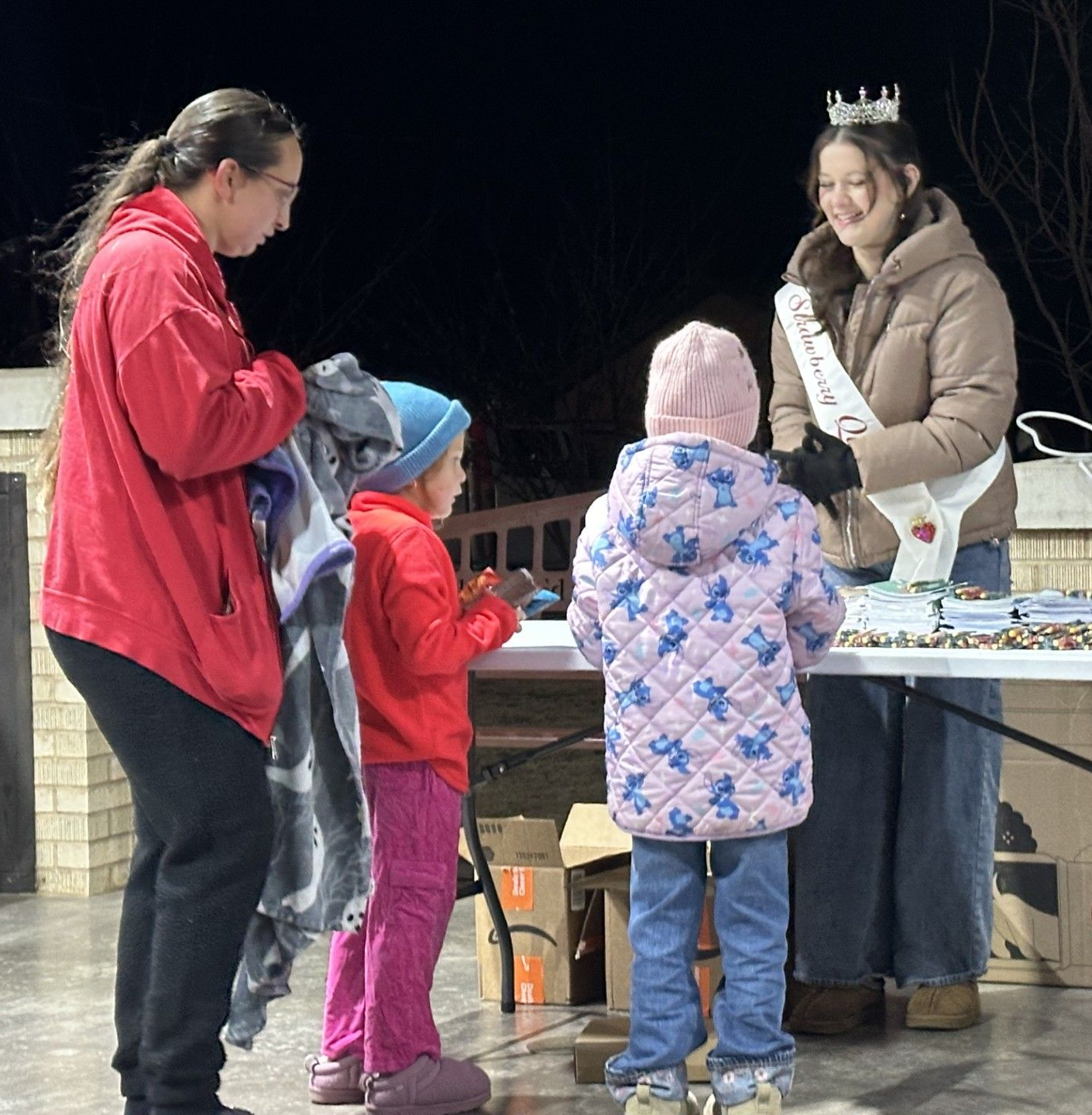 Strawberry Queen Karlee Jo Ingram hands out coloring books and crayons to children