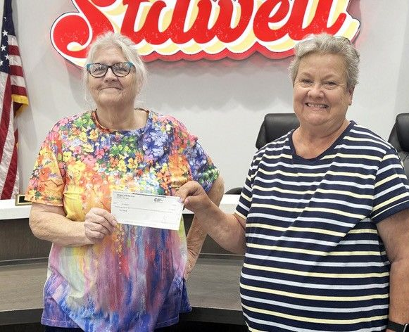 Stilwell Kiwanis President Tracey Sims presents Mayor Jean Ann Wright with a $5,000 donation toward the purchase of the swift water rescue boat.