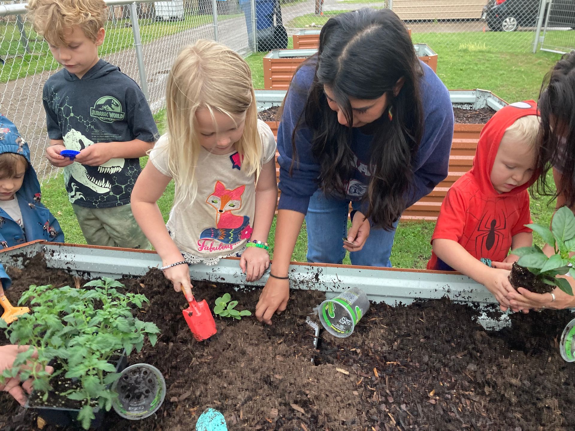 A group of children are planting plants in a garden.