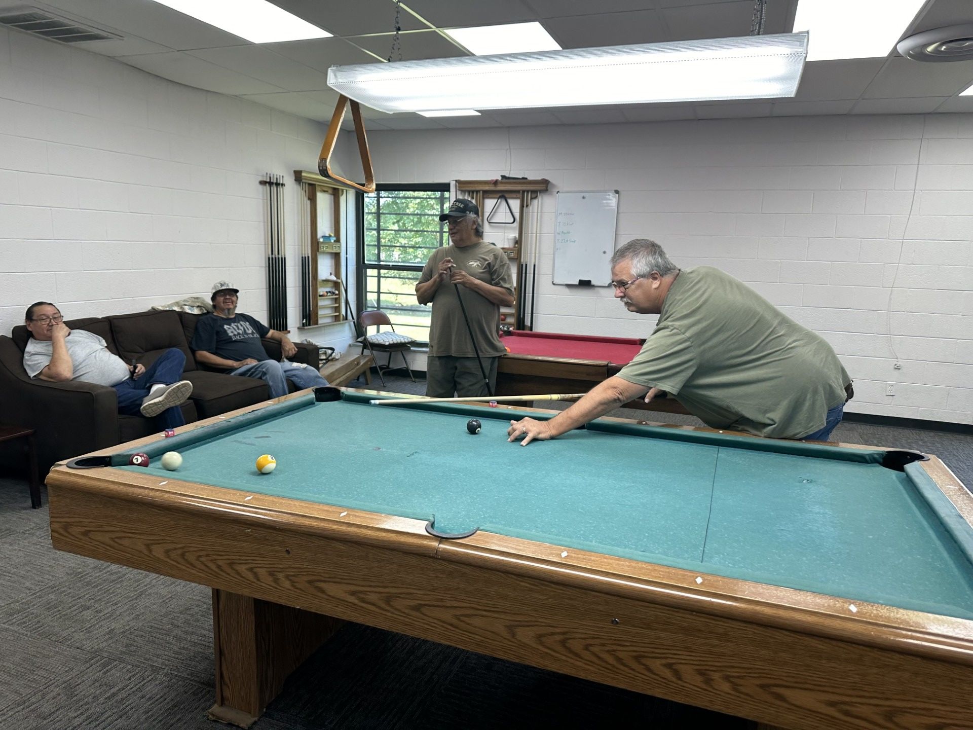 Marvin Grant and Roger Glass play a game of pool with spectators Gary Littledeer and Mitchell Glass.