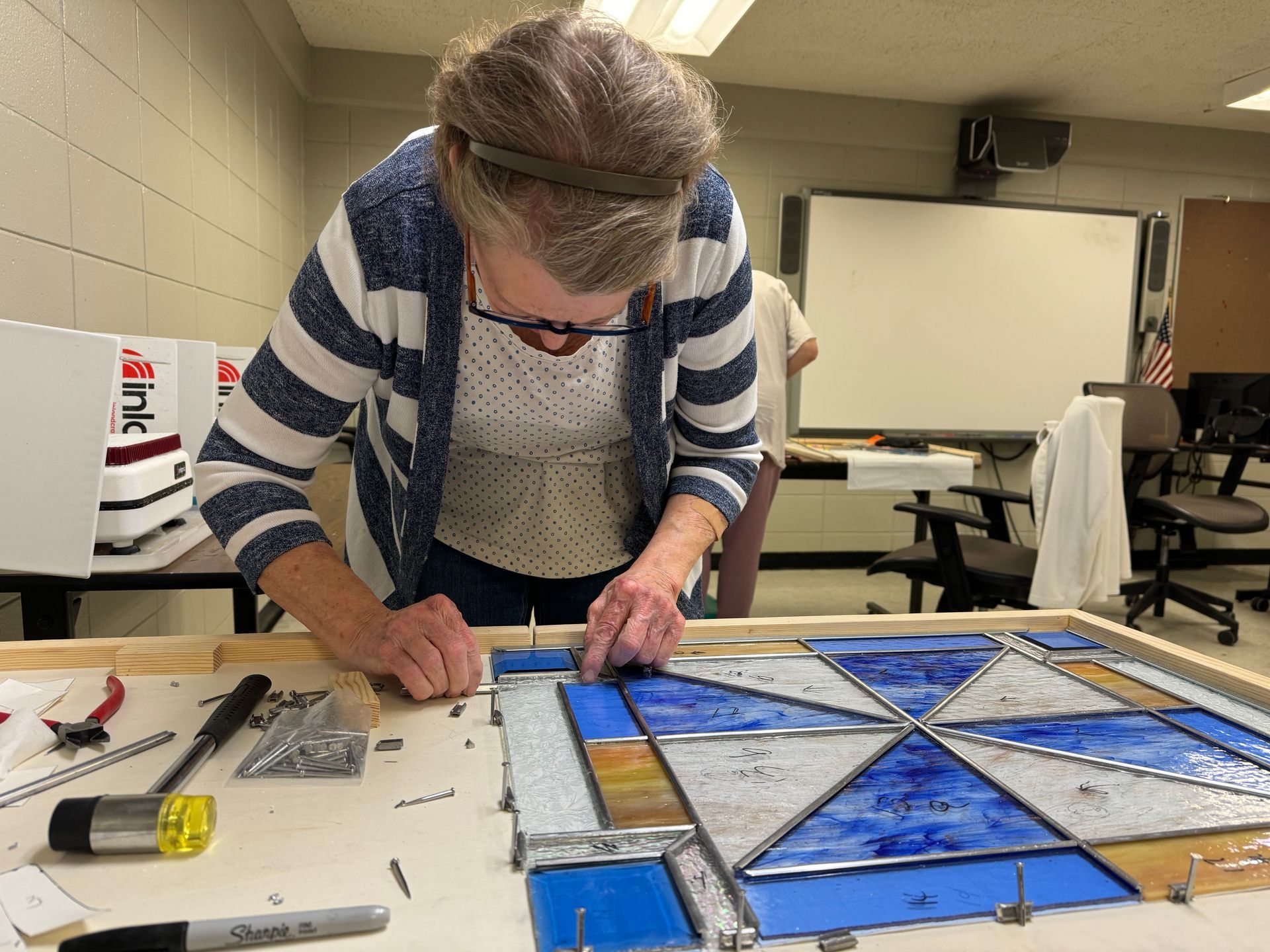 Sherry Wofford is shown fitting a piece of came onto the glass to secure it.