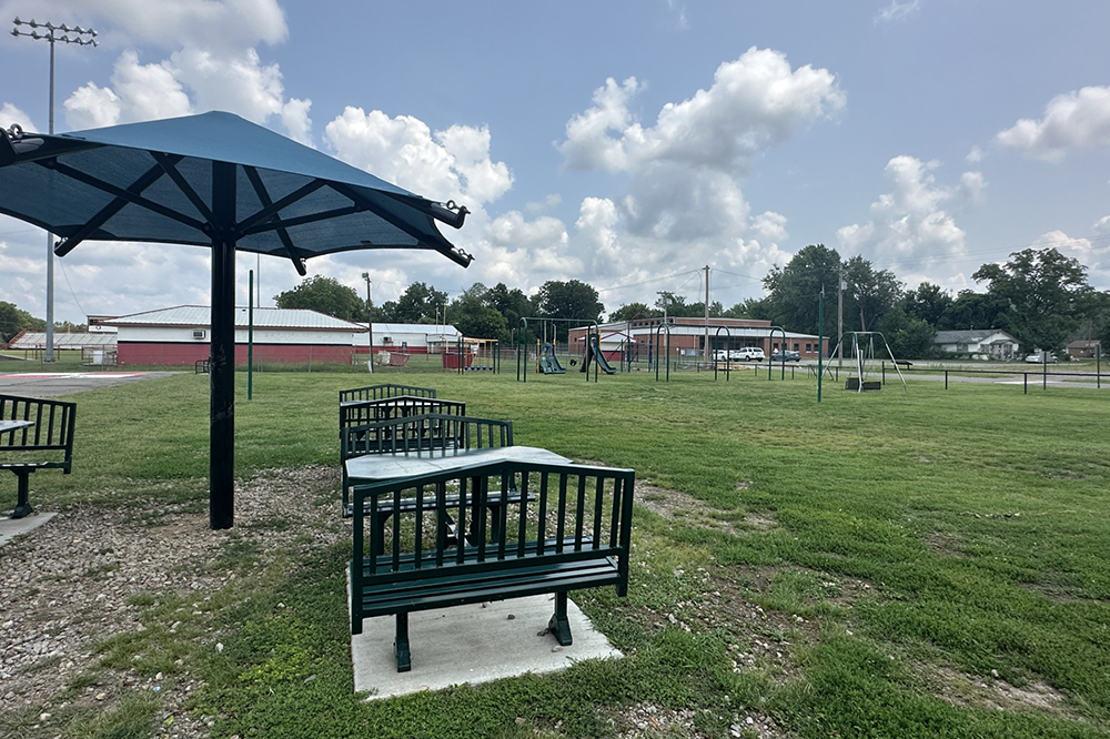 A park with tables and benches under an umbrella