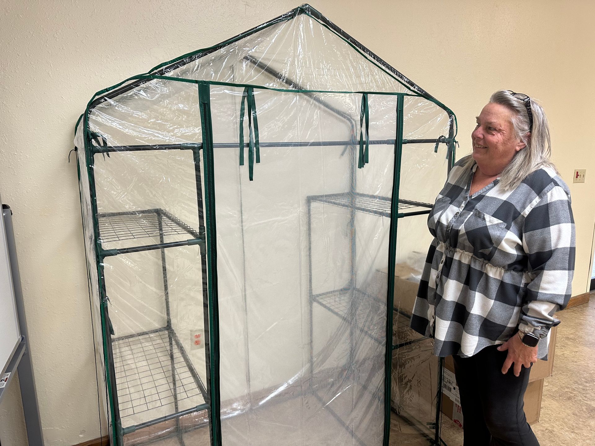 Rachelle Horney stands beside a greenhouse purchased for the community garden project the Stilwell Public Library is hosting