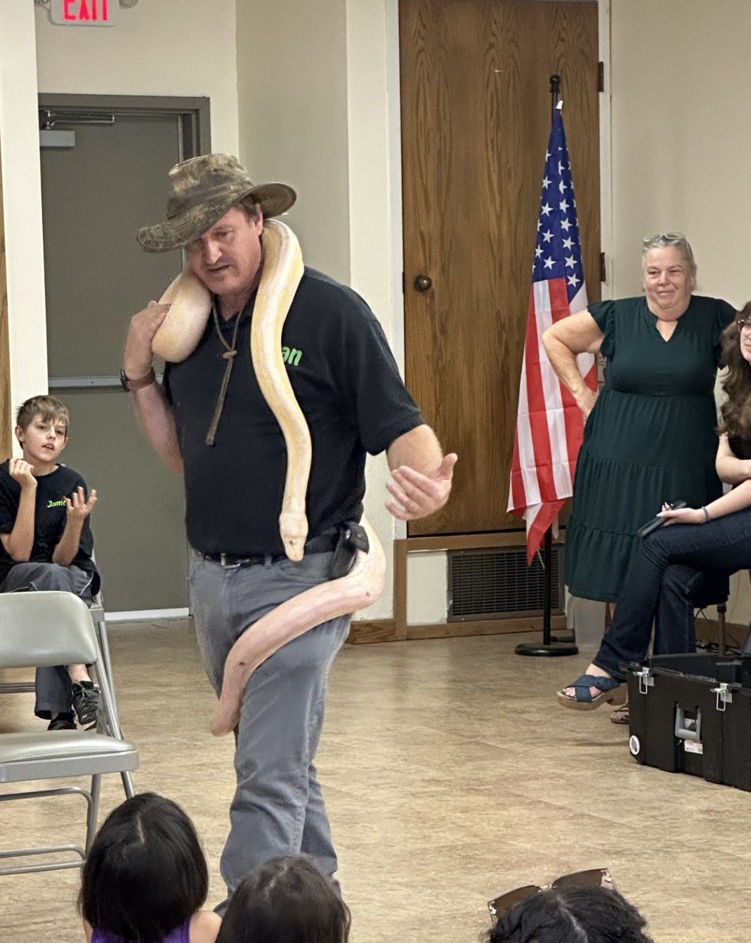 A man is holding a snake in front of a group of people.