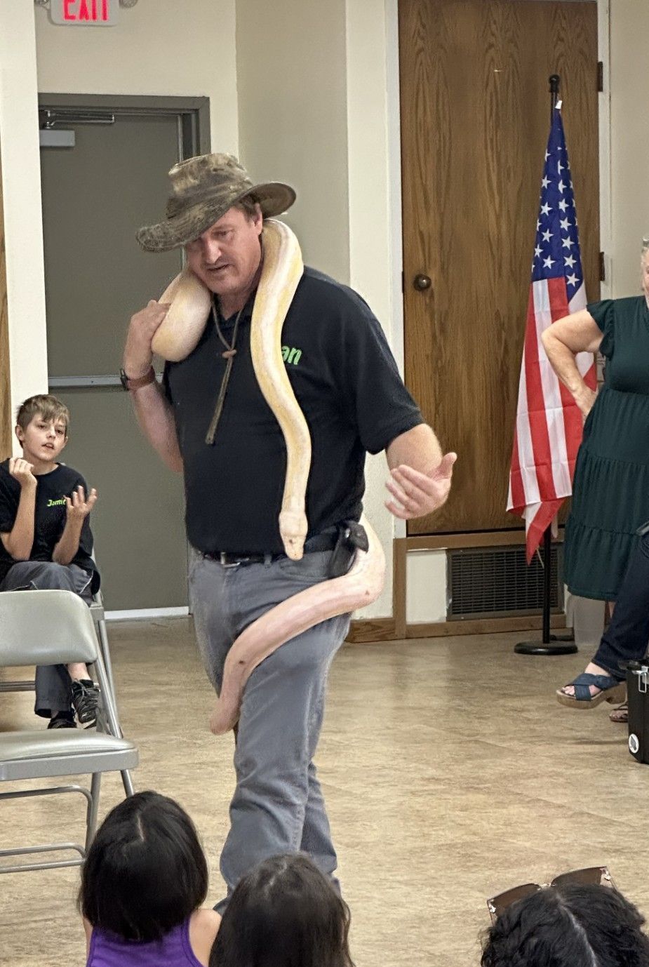 Man in hat holds a large cream-colored snake at an event