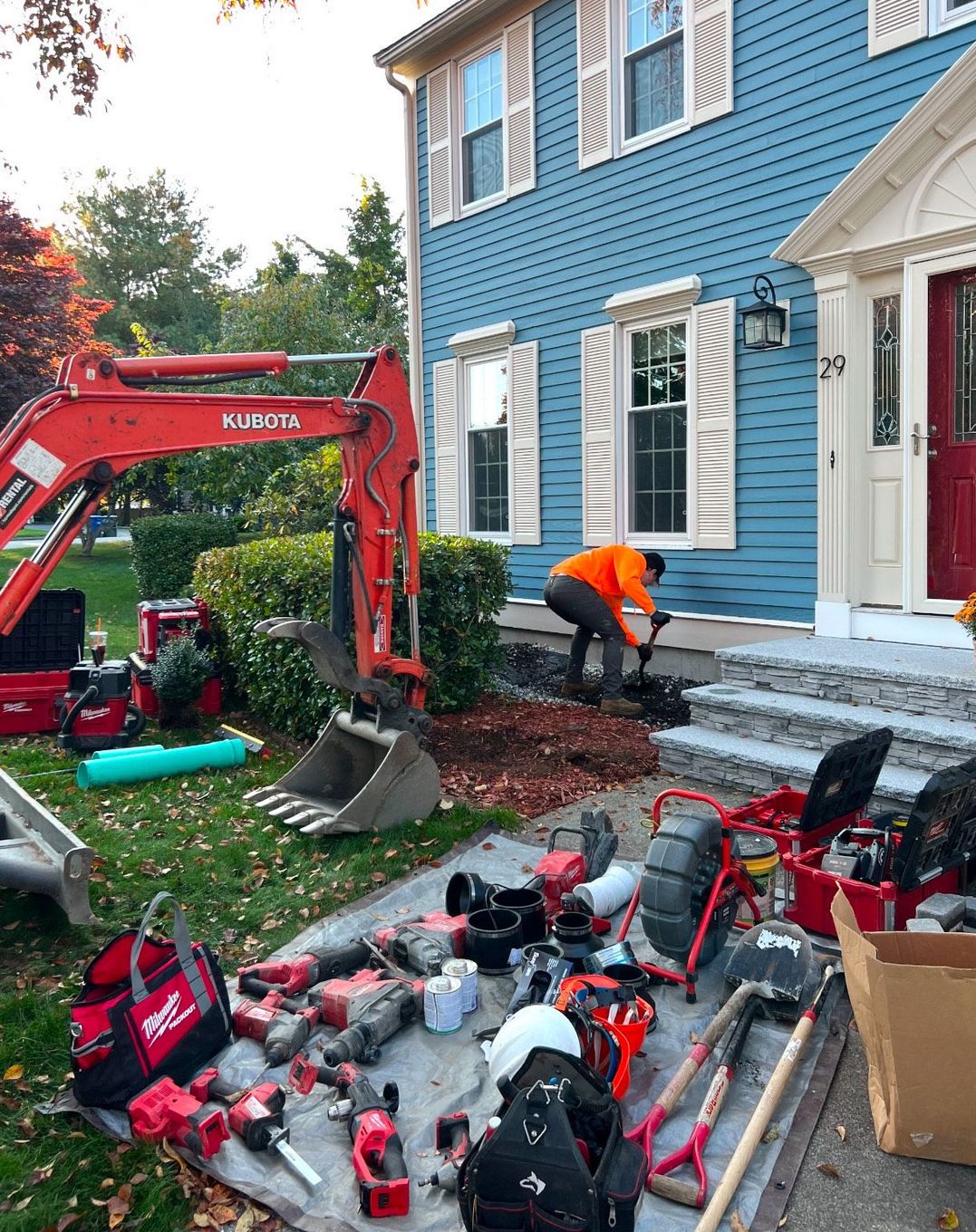 A man is digging a hole in front of a blue house.