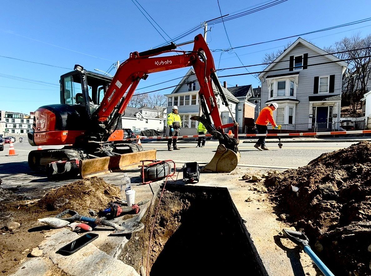 A bunch of white pipes are hanging from the ceiling in a basement.