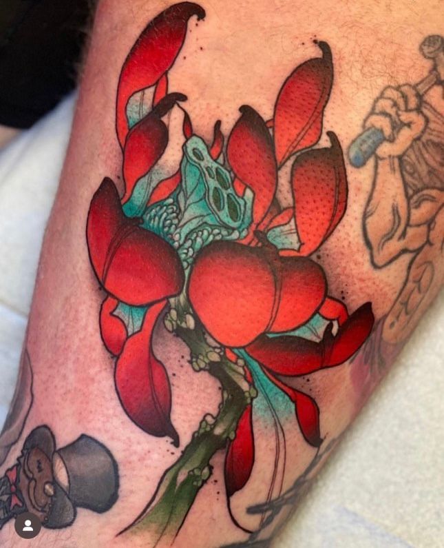 a tattoo of a red flower on a person's leg