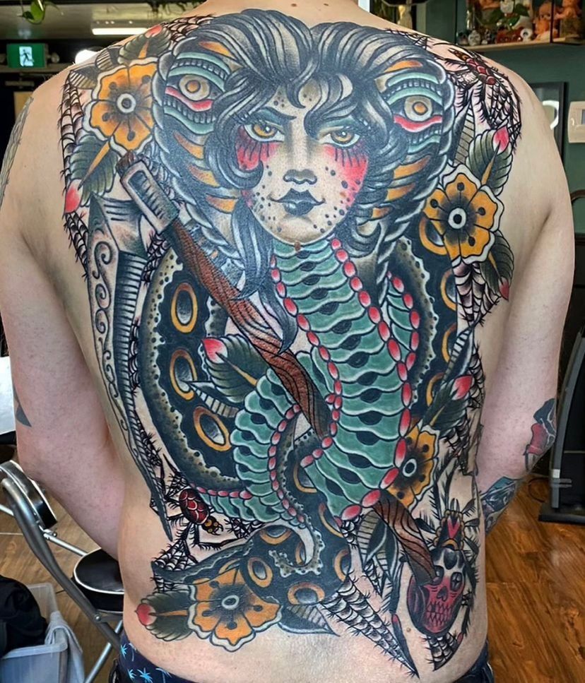 a man has a full back tattoo of a woman and a snake