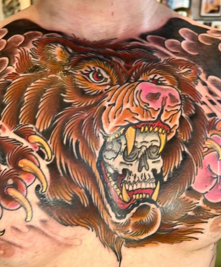 a man has a tattoo of a bear with a skull in its mouth